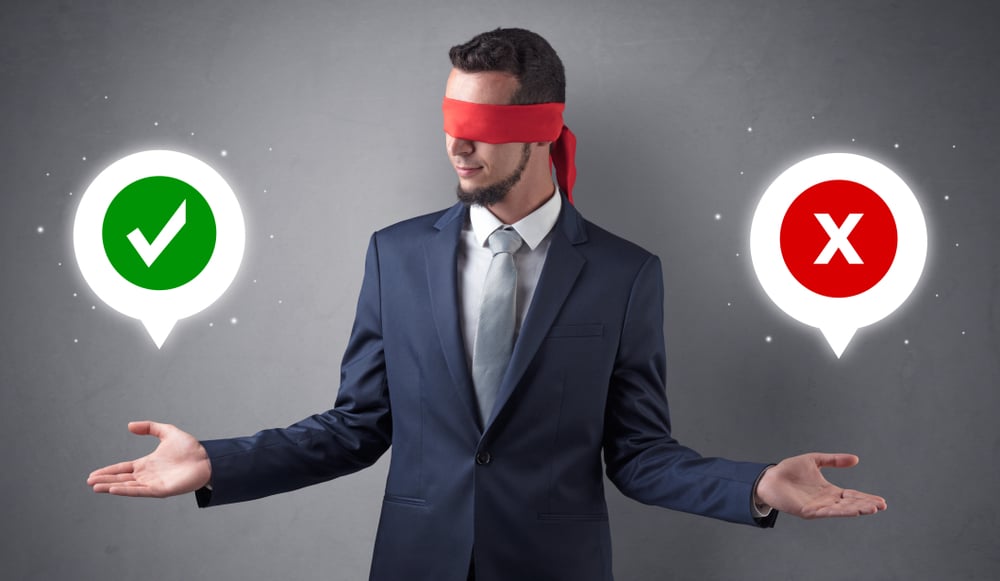 Blindfolded businessman with checked and x mark above his hand