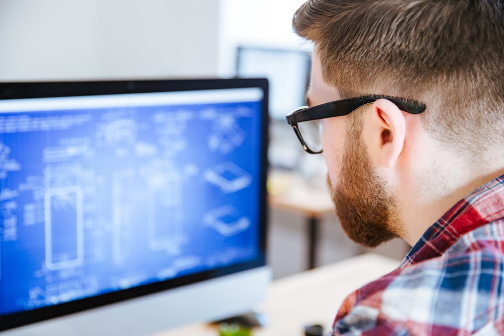 Closeup of young man in glasses with beard making blueprints on computer-3