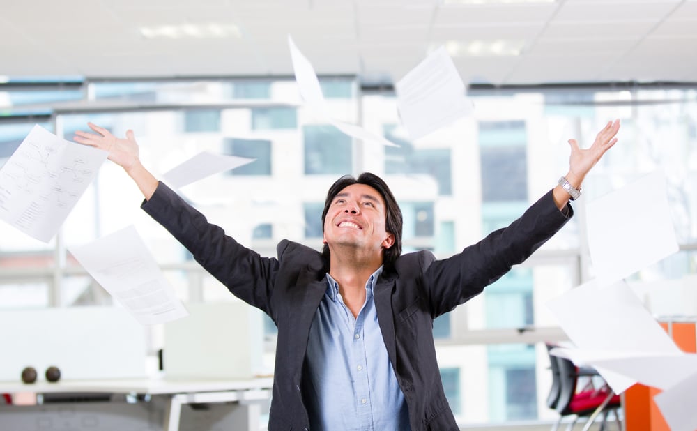 Excited businessman throwing papers at the office