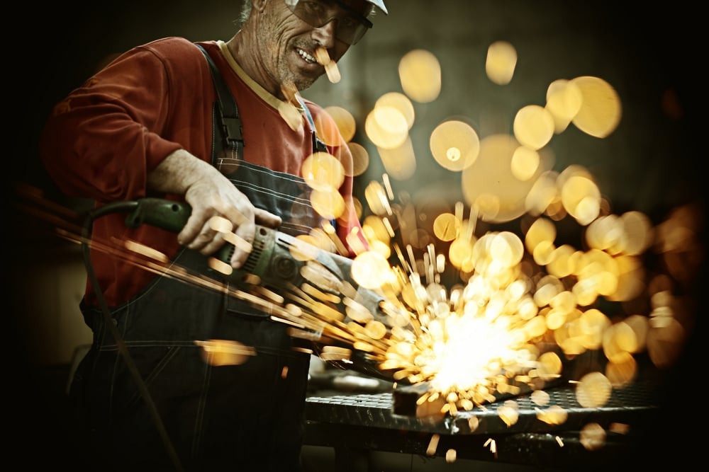 Industrial worker cutting and welding metal with many sharp sparks-1