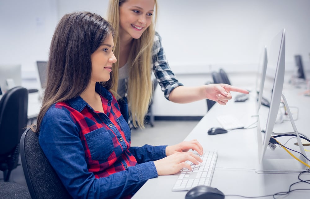 Smiling students using computer at university