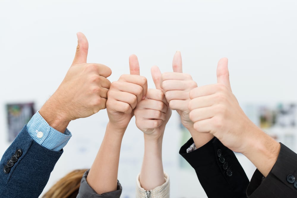 Successful diverse young business team giving a victorious thumbs up to show their success and motivation, close up view of their raised hands-1