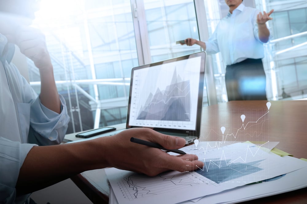 business documents on office table with smart phone and laptop computer and graph business with social network diagram and two colleagues discussing data in the background-3