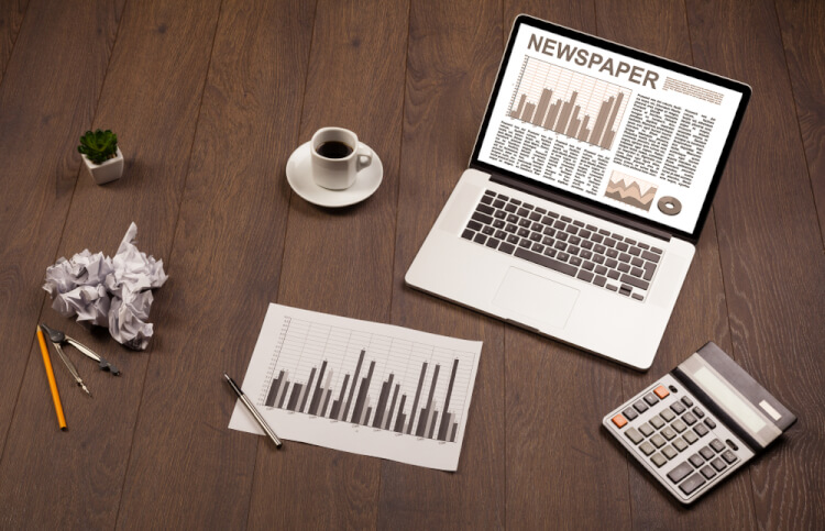 Business laptop with stock market report on wooden desk and accessories