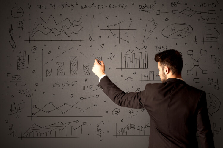 Young businessman in black suit standing in front of detailed calculations